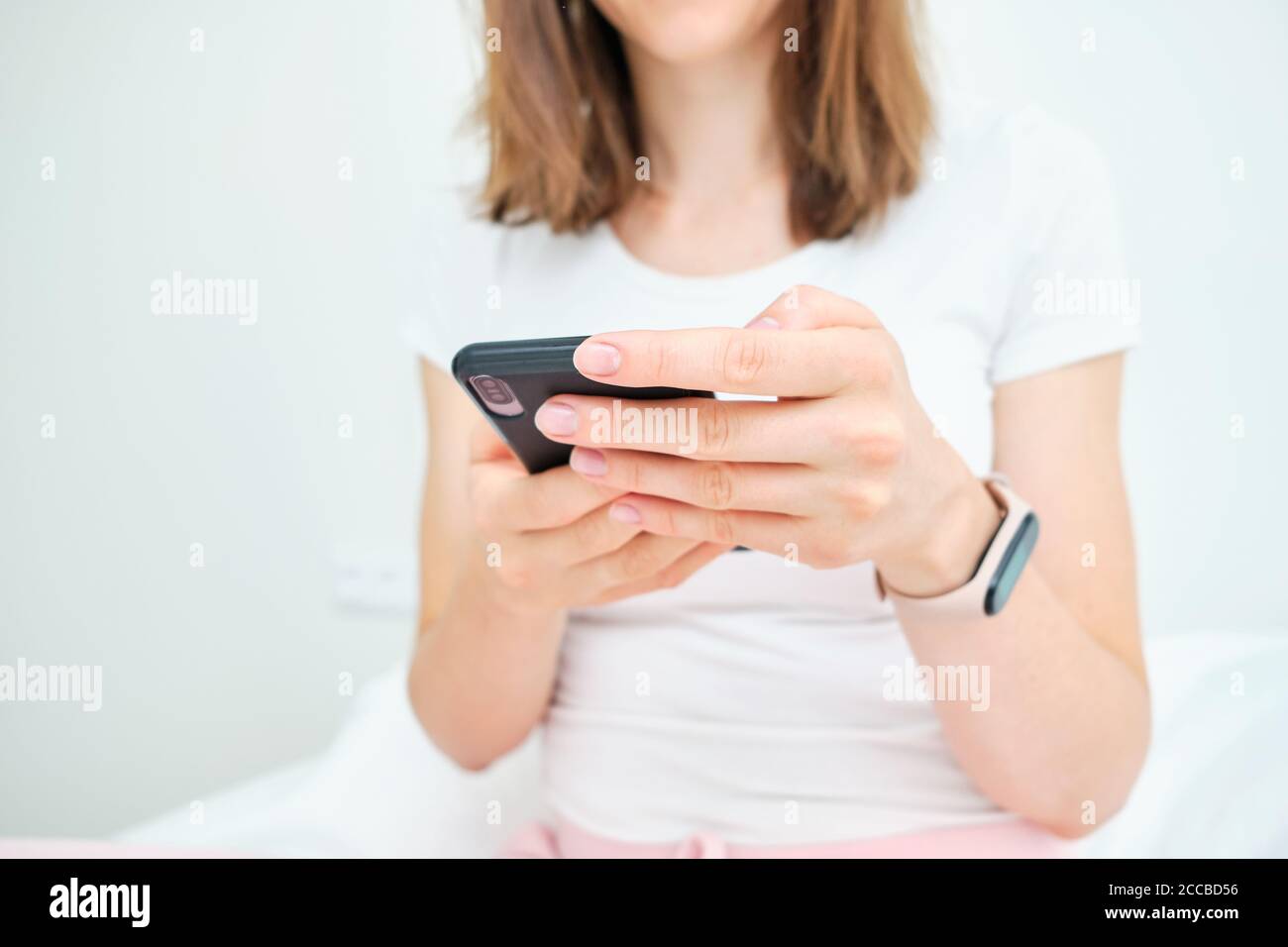 Une femme utilise un smartphone à la maison sur son lit. Banque D'Images