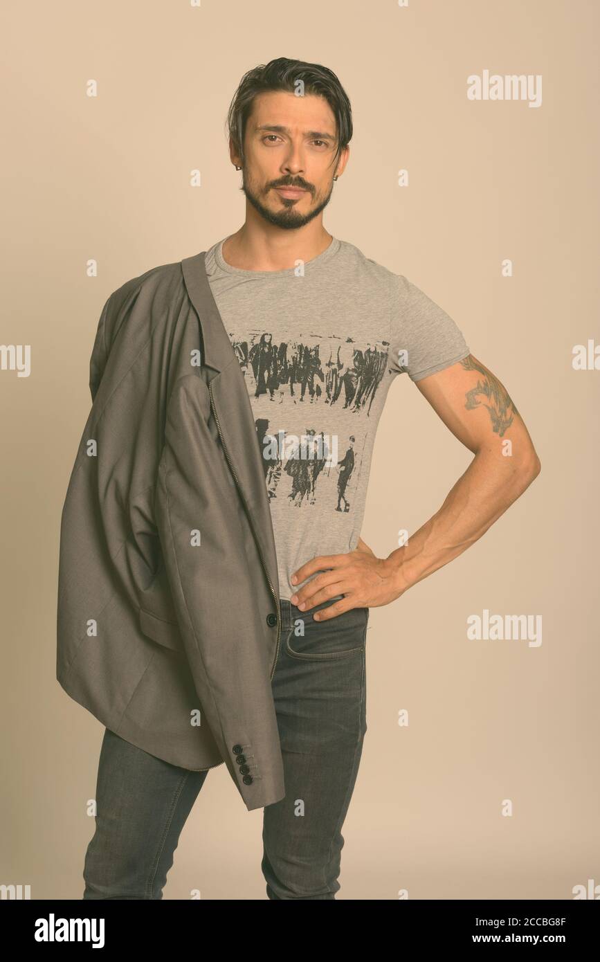 Photo de studio d'un beau homme posant avec une veste suspendue épaule Banque D'Images