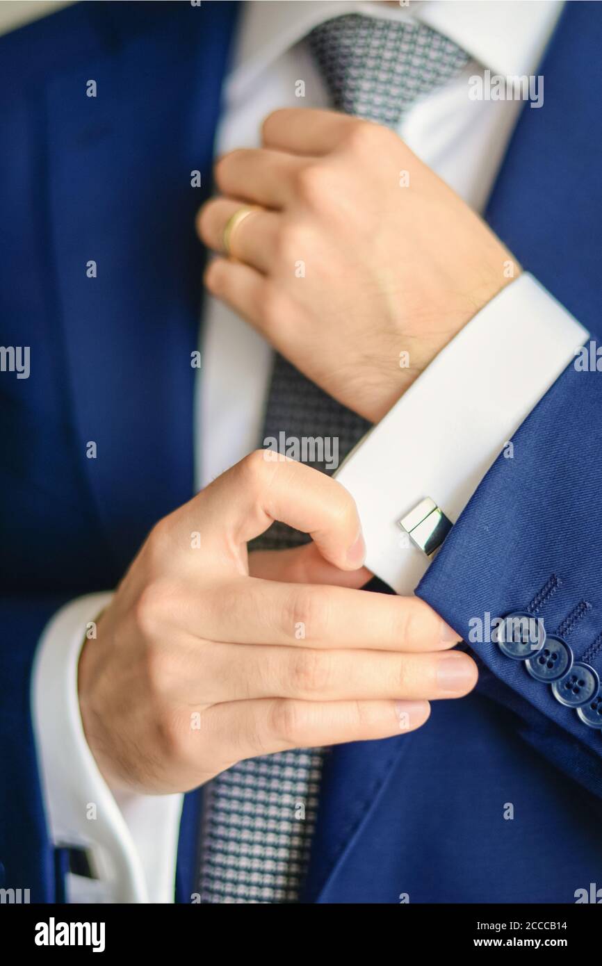 Le marié ou l'homme d'affaires fixe la tringle de manchette sur le poignet  du chemise portant un costume bleu Photo Stock - Alamy