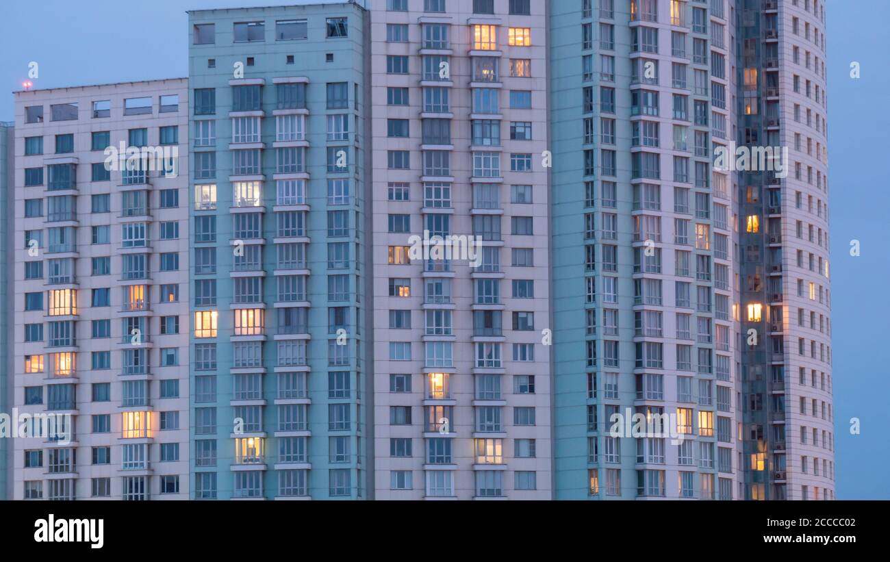 Fenêtres de l'immeuble d'appartements au crépuscule. En soirée, vue extérieure sur la façade du salon avec éclairage chaleureux. Architecture, concept urbain Banque D'Images