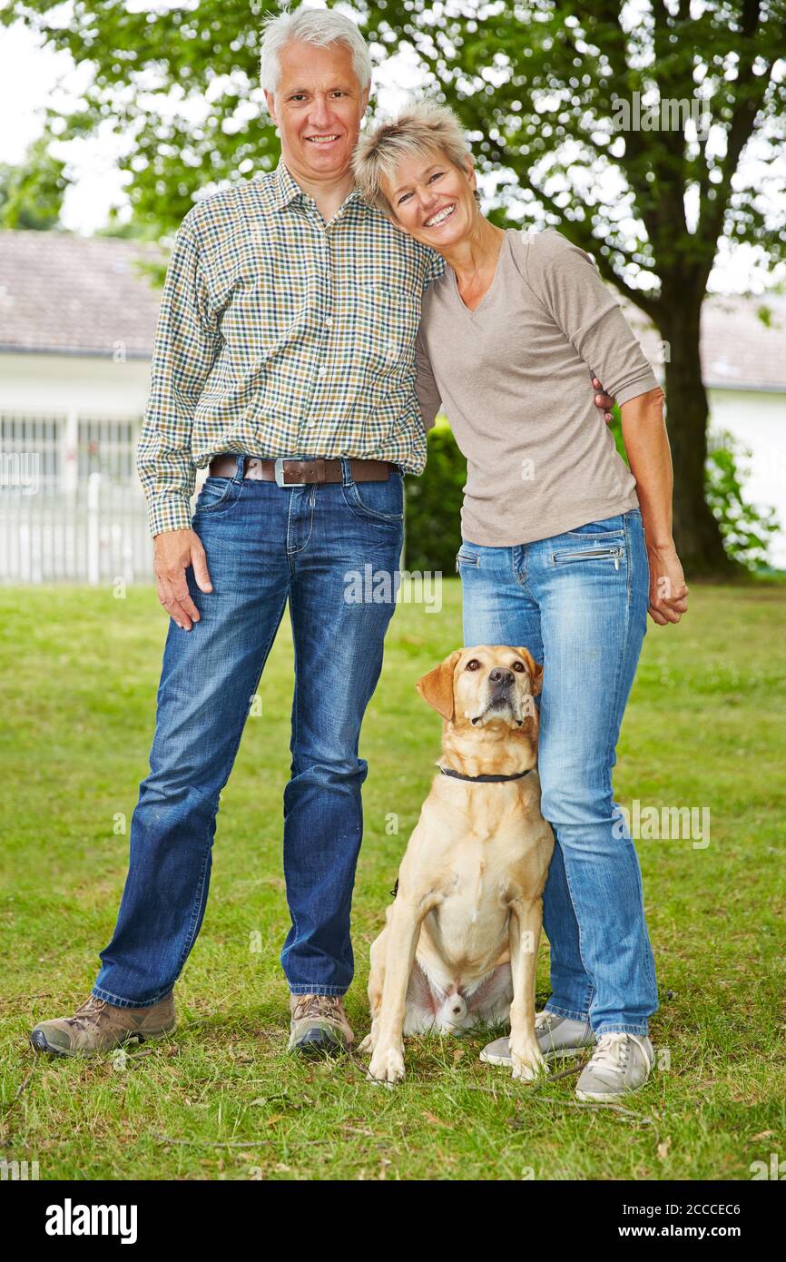 Couple heureux de personnes âgées avec la maison et le chien se tient dans le jardin Banque D'Images