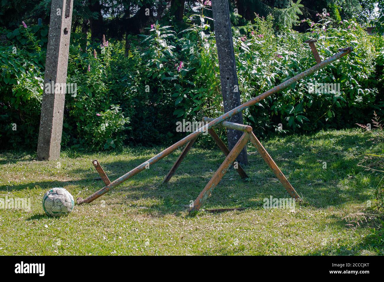 Aire de jeux abandonnée par une journée ensoleillée. Vous pouvez voir une oscillation cassée et un football sans air. Banque D'Images