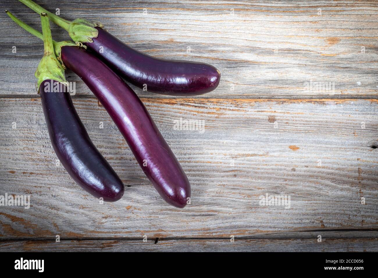 Solanum melongena, aubergine asiatique crue, sur une table en bois rustique planche Banque D'Images