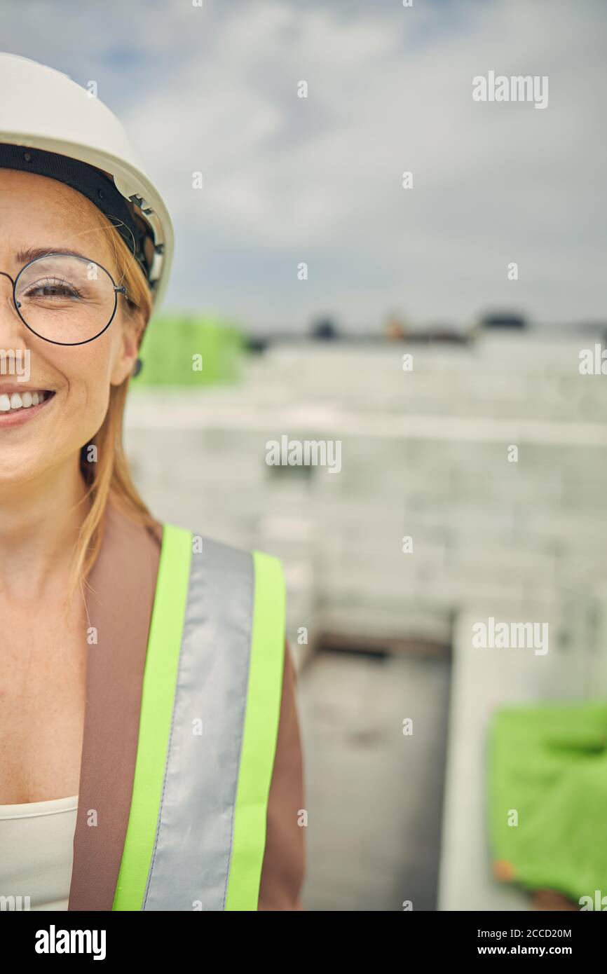 Femme de construction heureuse en lunettes debout à l'extérieur Banque D'Images