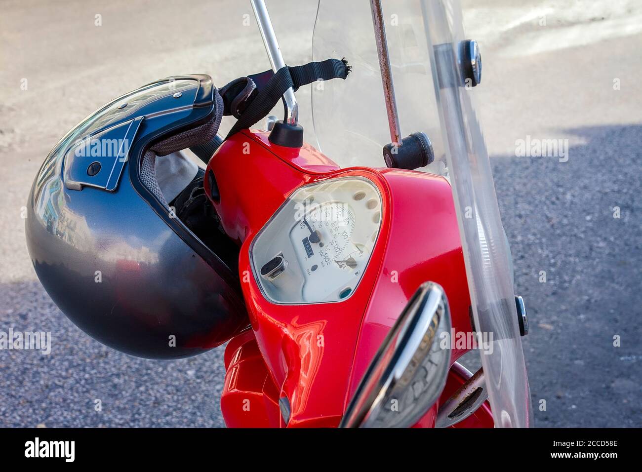 Cuisinière rouge. Isolé, gros plan de la moto rouge avec un casque suspendu au-dessus de la barre chromée. Image de stock. Banque D'Images