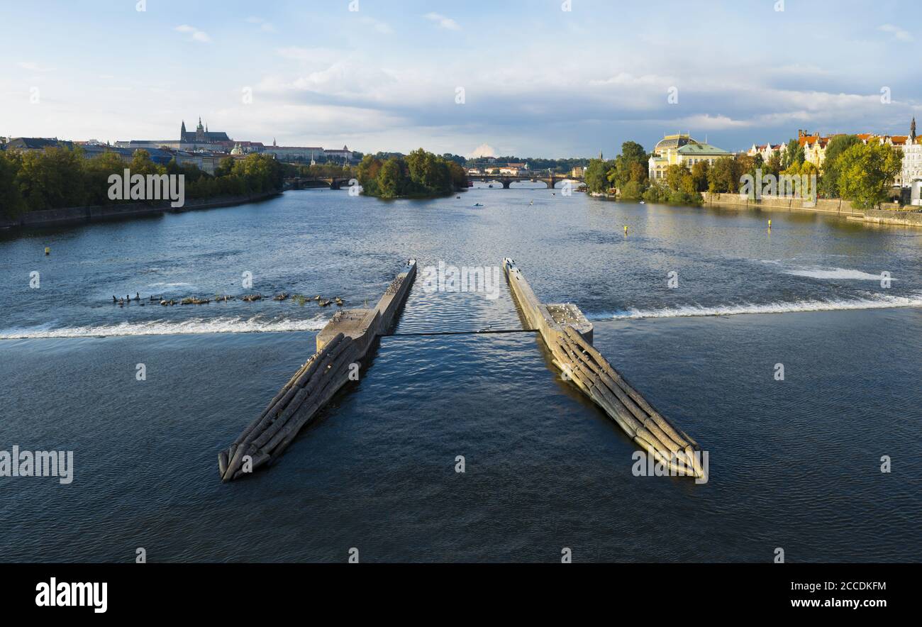 Stitkovsky weir, Vltava, Prague, République Tchèque / Tchéquie - le belin dans le centre de l'eau. Ville avec le monument du château de Prague en arrière-plan. Banque D'Images