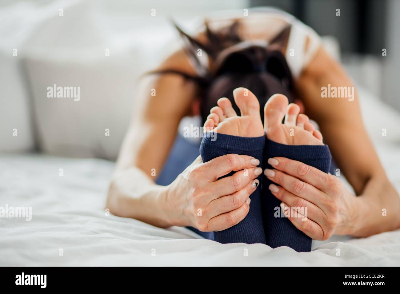 photo en gros plan des jambes de la jeune femme tout en s'étirant sur le lit à la maison, mode de vie sain et concept de yoga Banque D'Images