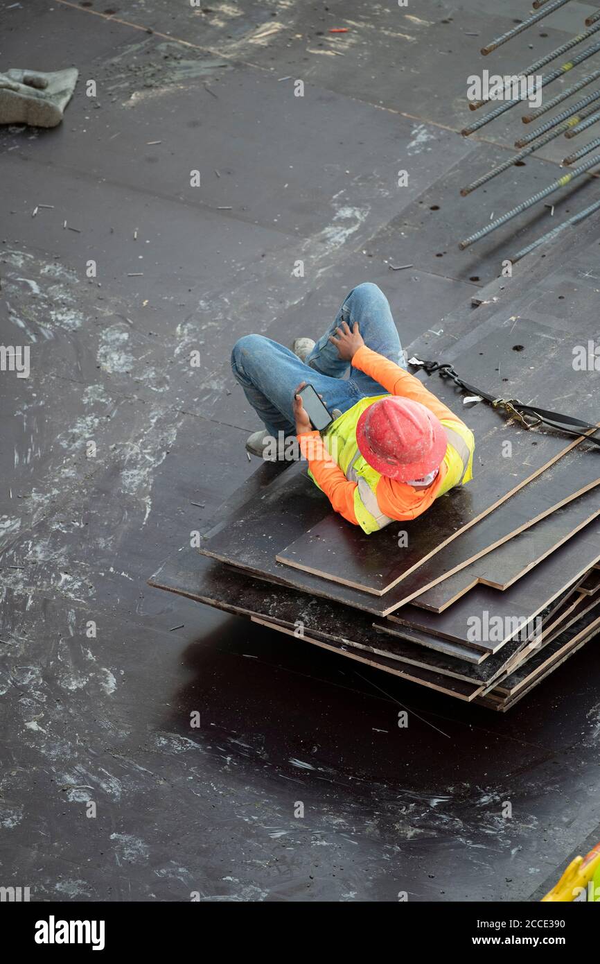 Austin, TX USA 25 juillet 2020: Un membre de l'équipage en béton regarde son téléphone cellulaire tout en prenant une pause après avoir travaillé sur le parking d'un immeuble de 53 étages pendant une nuit dans le centre-ville d'Austin, TX. D'énormes projets de construction se poursuivent sans relâche au Texas malgré la pandémie de COVID-19 à l'échelle nationale et l'État frappé par plus d'un demi-million de cas et plus de 10,000 000 décès. Banque D'Images