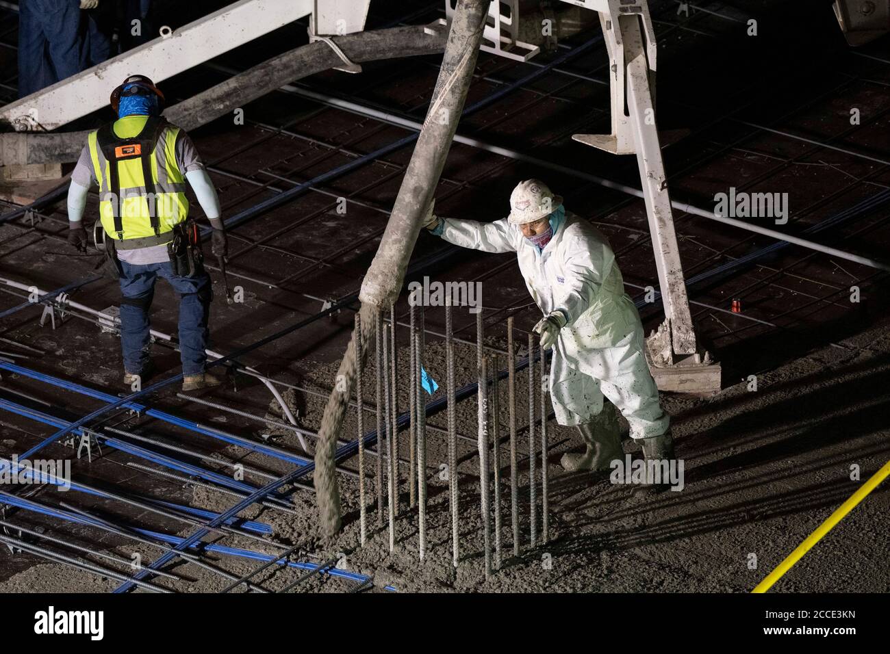 Austin, TX USA 25 juillet 2020: Le béton pompé coule à travers un tube sur le plancher d'un garage de stationnement, partie d'un bâtiment de 53 étages en construction, pendant une nuit-verse près du centre-ville d'Austin,. Banque D'Images