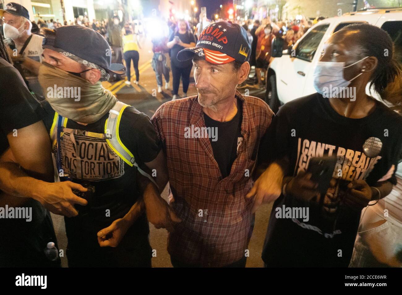 Tulsa, OK, États-Unis. 20 juin 2020 : UN partisan de Trump et des manifestants Black Lives Matter relient les armes pour empêcher la foule d'approcher les policiers. Banque D'Images