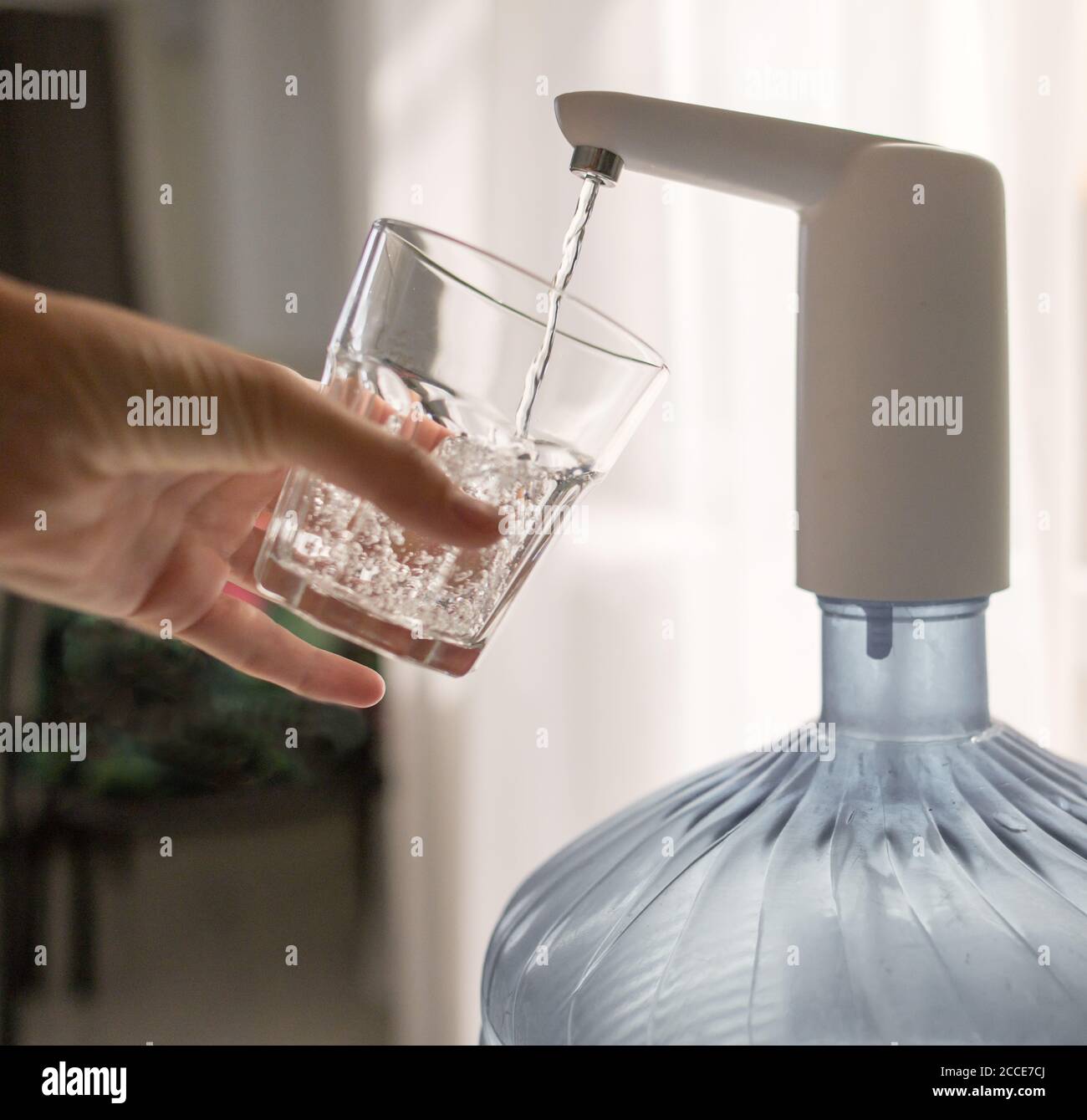 la main avec un verre verse l'eau du refroidisseur Banque D'Images