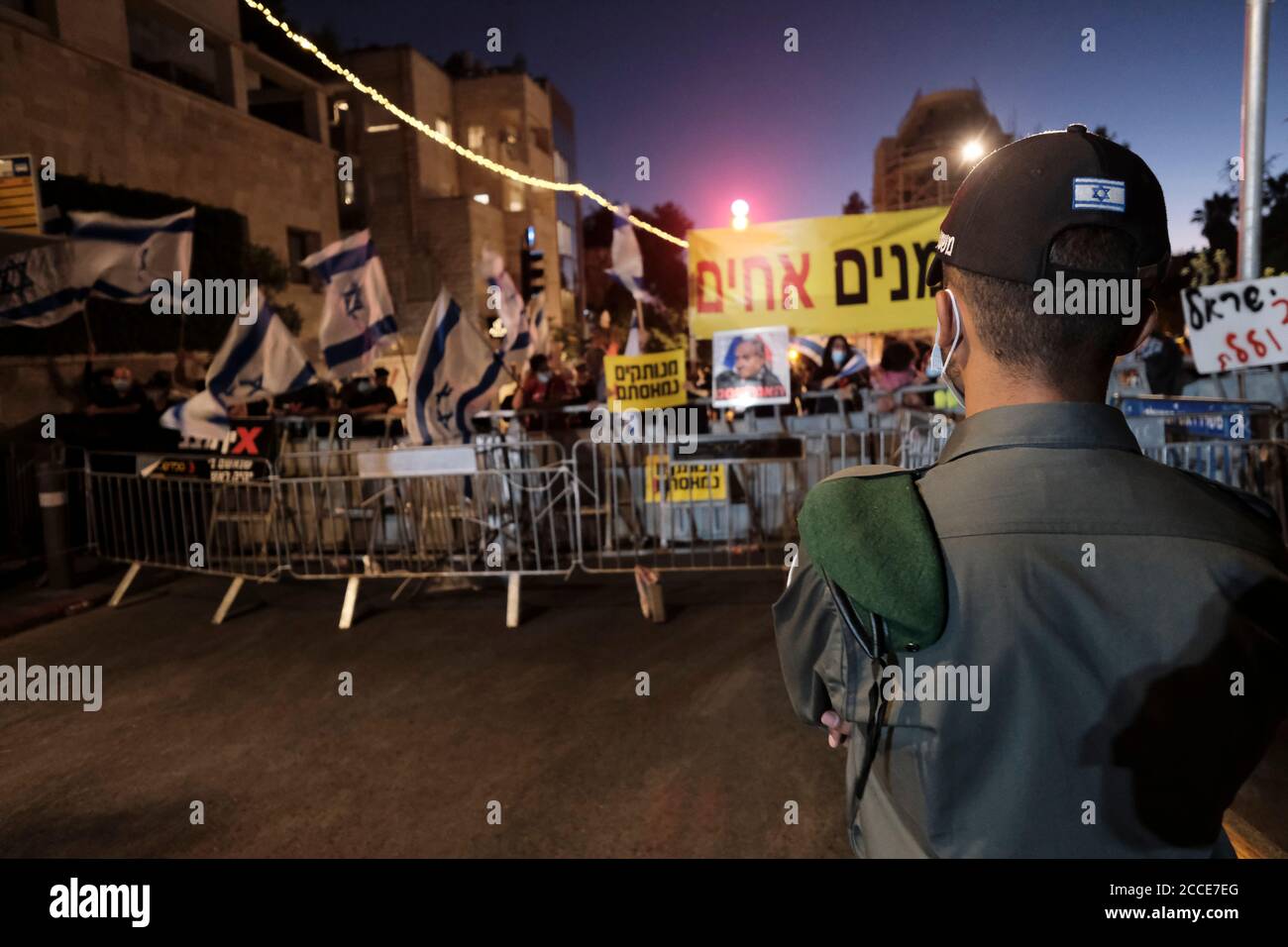 JÉRUSALEM, ISRAËL - 20 AOÛT : la police fait observer que les manifestants branchent des pancartes et crient des slogans lors d'une manifestation contre le Premier ministre Benjamin Netanyahou à la suite de son inculpation pour corruption et manipulation de la pandémie du coronavirus devant la résidence officielle du Premier ministre le 20 août 2020 à Jérusalem, en Israël. Netanyahou est jugé pour une série de cas dans lesquels il aurait reçu des cadeaux somptueux de la part d'amis milliardaires et échangé des faveurs réglementaires avec des magnats des médias pour une couverture plus favorable de lui-même et de sa famille. Banque D'Images