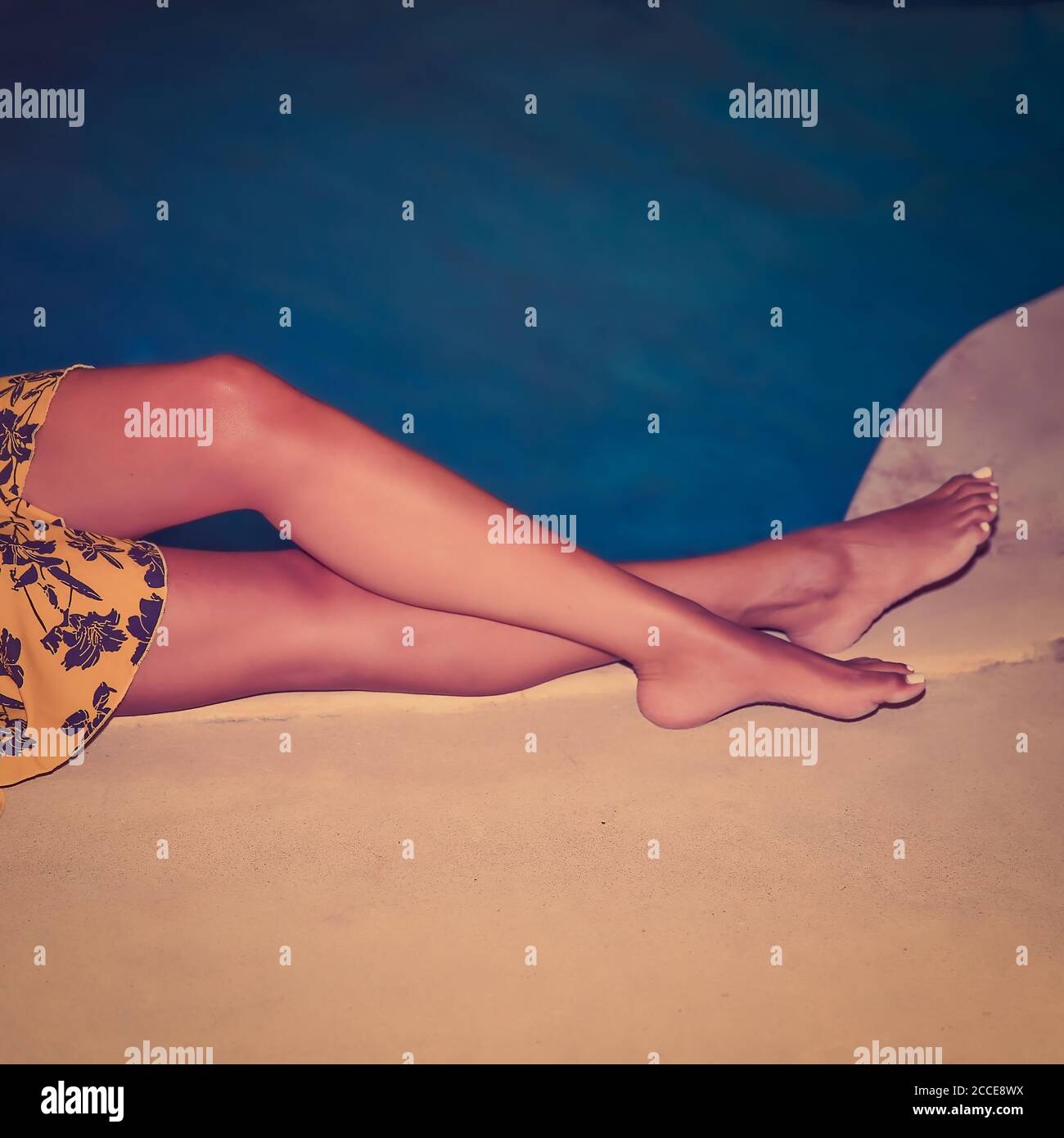 Des jambes bronzées se détendent près de l'eau. Image de stock. Banque D'Images