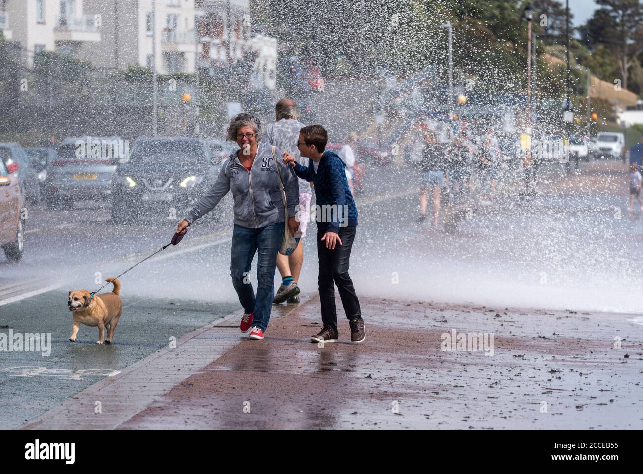 Les gens qui marchent un chien à Southend sur la mer, Essex, au Royaume-Uni, pendant les vents forts de Storm Ellen, se mouiller de la vague qui s'est écrasant. Route, voitures, circulation Banque D'Images