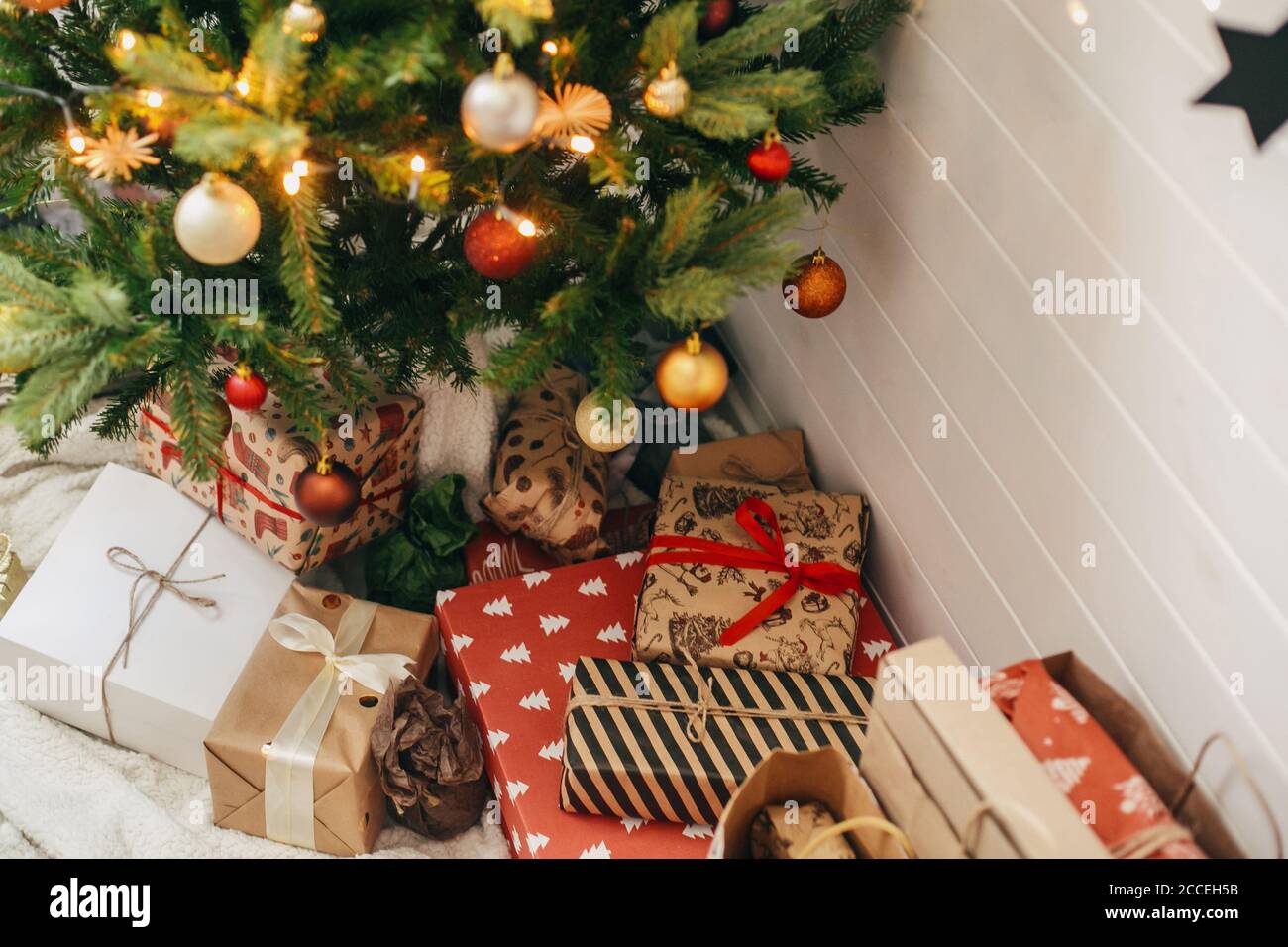 Joyeux Noël. Cadeaux de noël élégants sous un sapin de Noël. Boîtes-cadeaux  enveloppées dans du papier moderne artisanal et arbre décoré avec des  boules rouges et dorées i Photo Stock - Alamy
