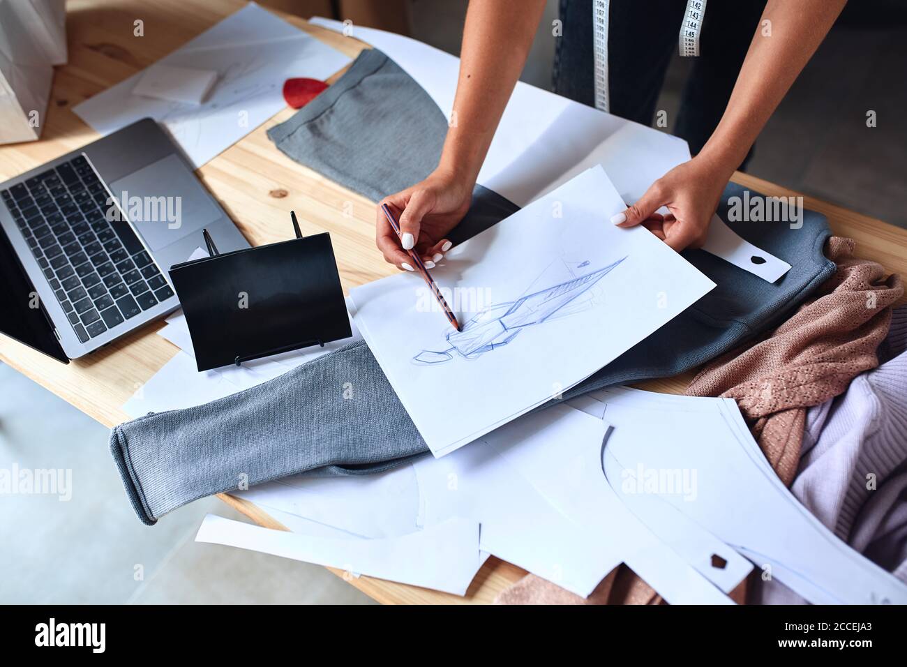 Vue de dessus sur la création d'un croquis pour la nouvelle collection de mode. Ordinateur portable, papier, textile sur table Banque D'Images