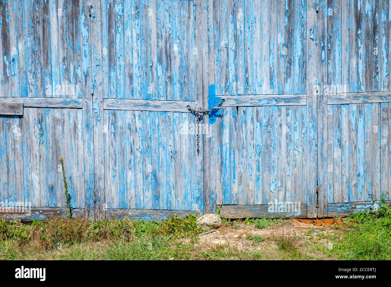 Porte de garage abîmé avec peinture bleue écaillée verrouillée avec un chaîne Banque D'Images