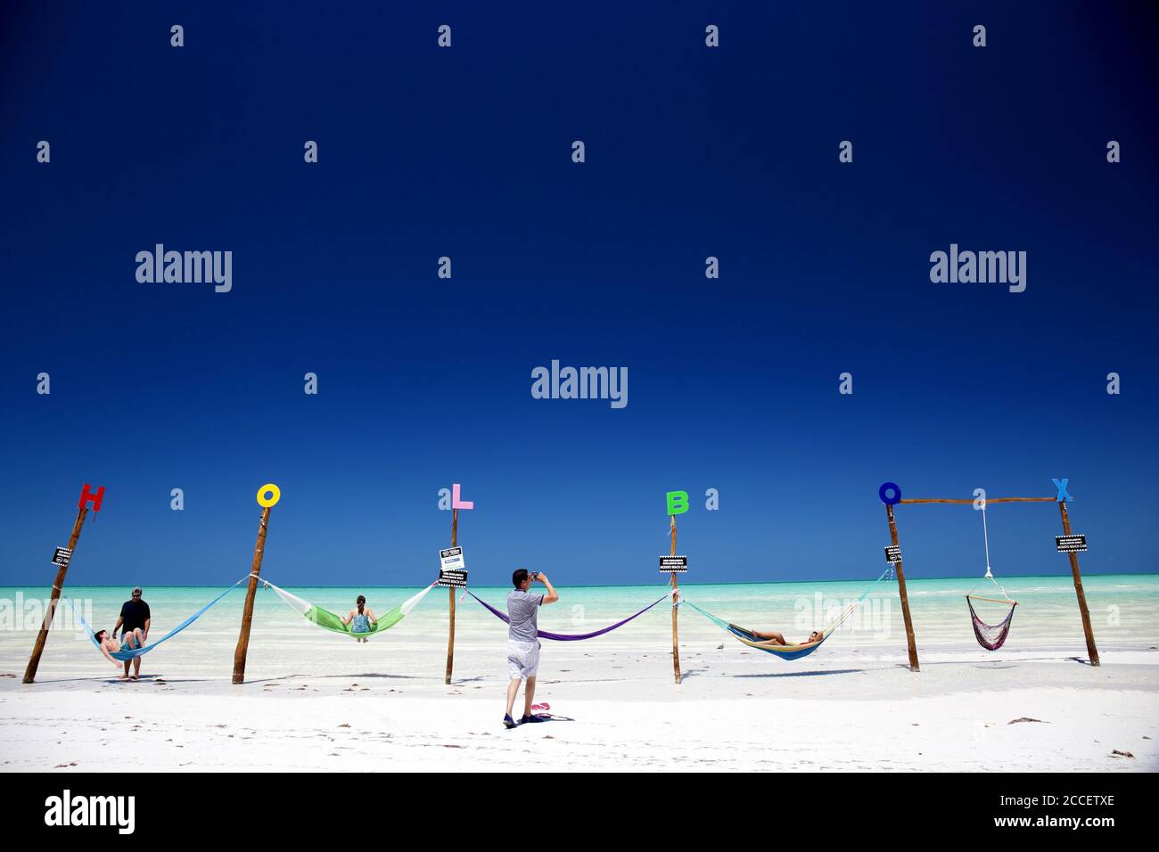 Les touristes prenant des photos dans des hamacs sur une plage idyllique sur l'île de Holbox. Banque D'Images