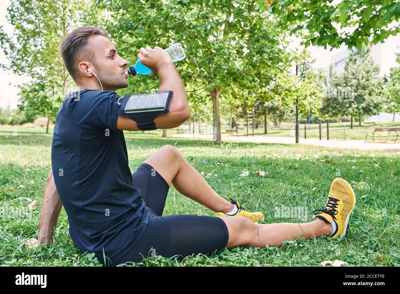 Homme buvant un verre de sport après l'entraînement. Il est dans un parc extérieur. Banque D'Images