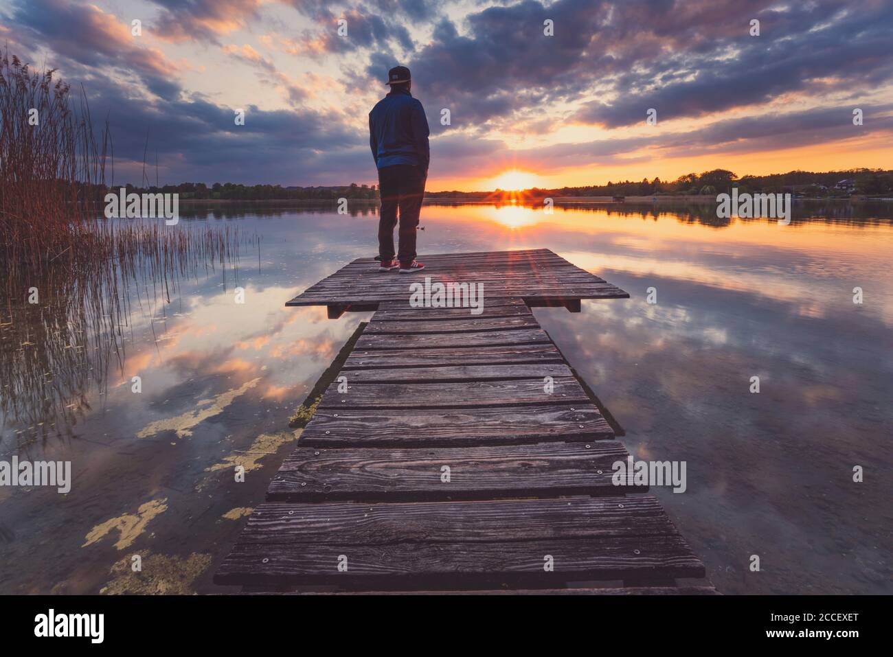 Europe, Allemagne, Bavière, Breitbrunn, Chiemsee, Chiemgau, Lac de Chiemsee, Homme debout sur la jetée et regardant le coucher du soleil, Banque D'Images
