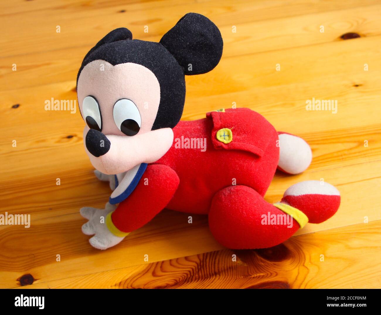 Mickey Mouse Un Jouet A Piles Pour Bebe Officiel De Disney Un Bavoir Et Un Bebe Rouge Poussent Sur Un Bois Sol Photo Stock Alamy