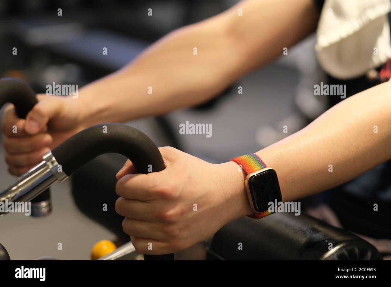 gros plan du bras de l'homme portant une montre intelligente, s'exerçant sur un équipement de gym. arrière-plan flou Banque D'Images
