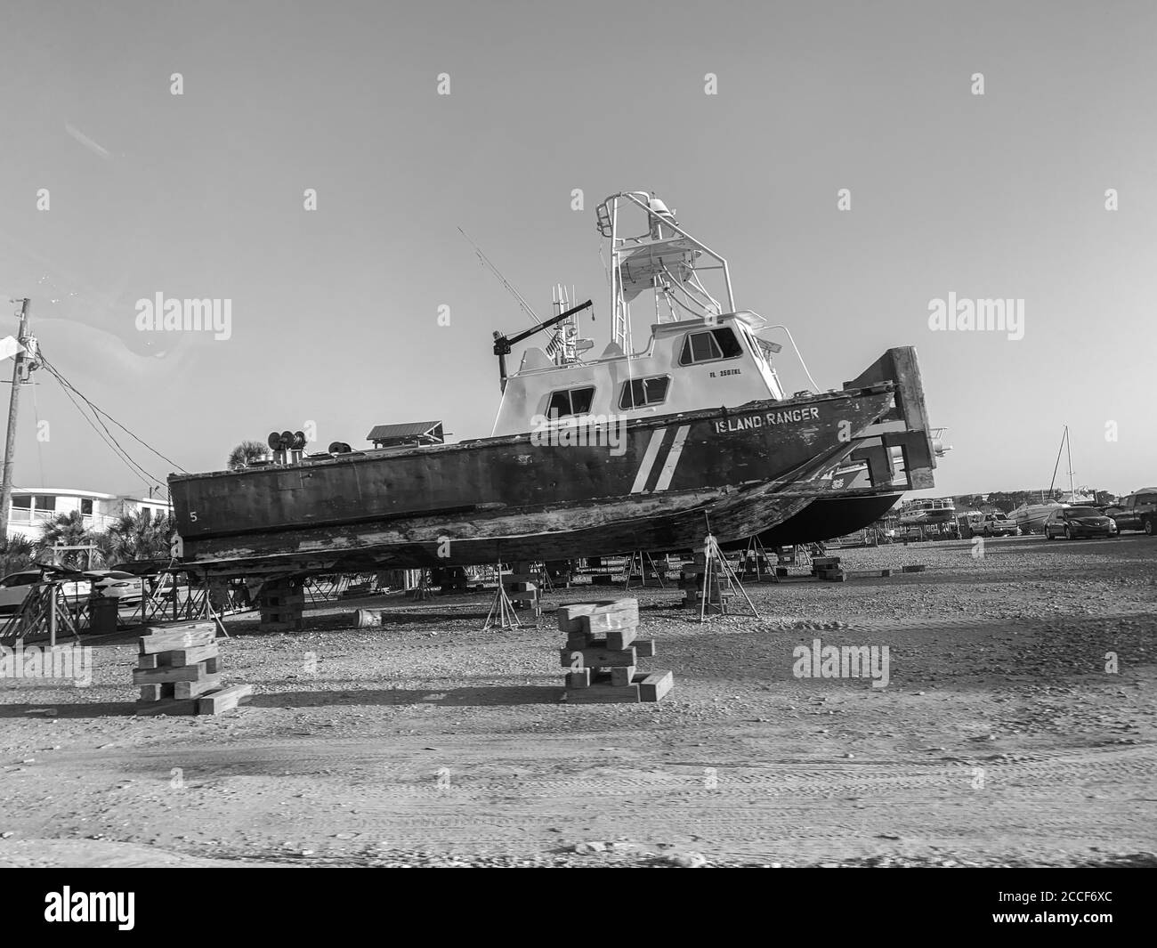 Image en noir et blanc d'un bateau de pêche stationné dans un parc de bateaux. Le bateau est hors de l'eau, ce qui vous permet de voir tout le bateau. Banque D'Images