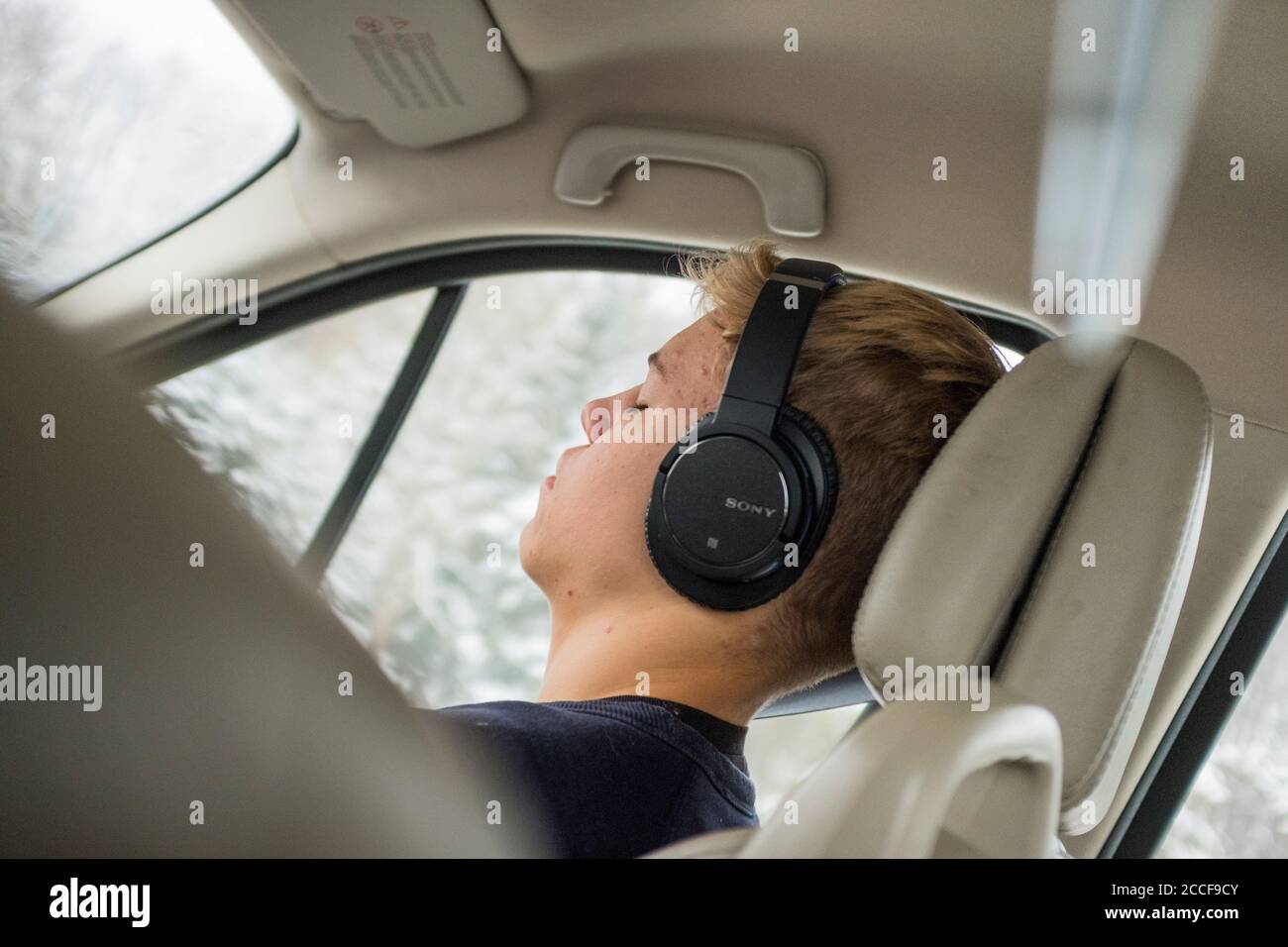 Garçon (16 ans) avec casque dans une voiture Banque D'Images