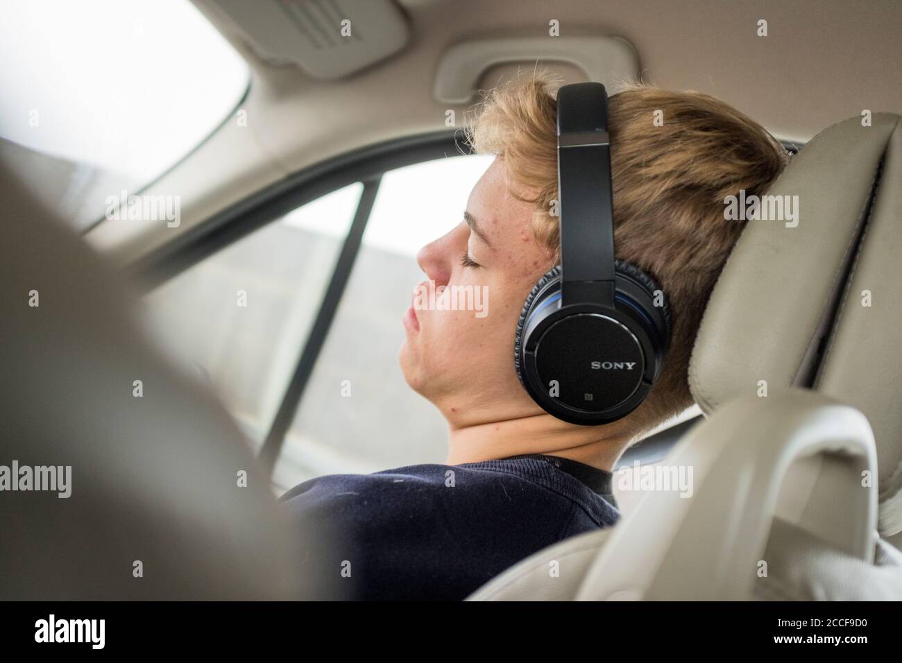 Garçon (16 ans) avec casque dans une voiture Banque D'Images