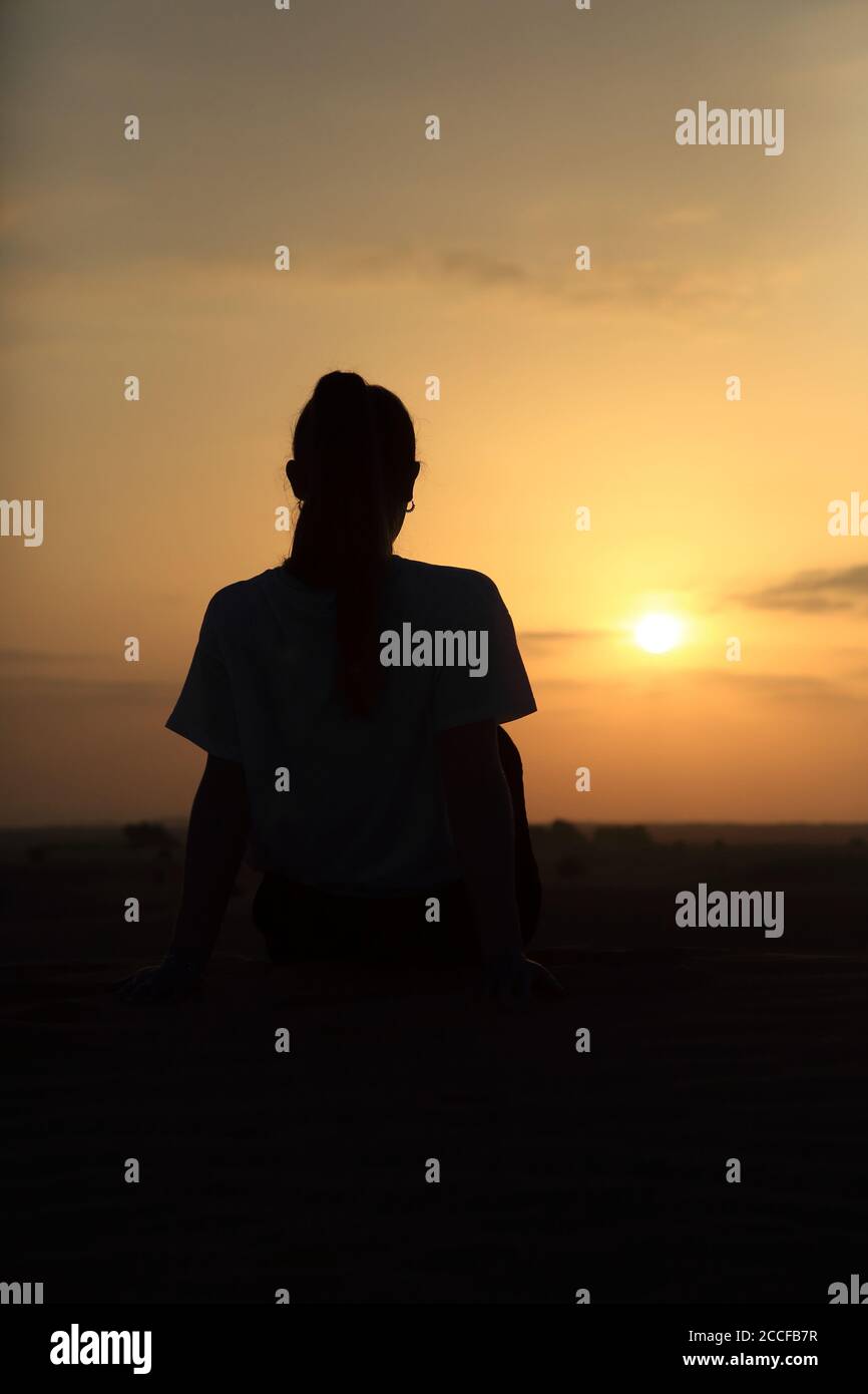 Femme silhoueted, lever du soleil dans le désert à Abu Dhabi, Émirats Arabes Unis Banque D'Images
