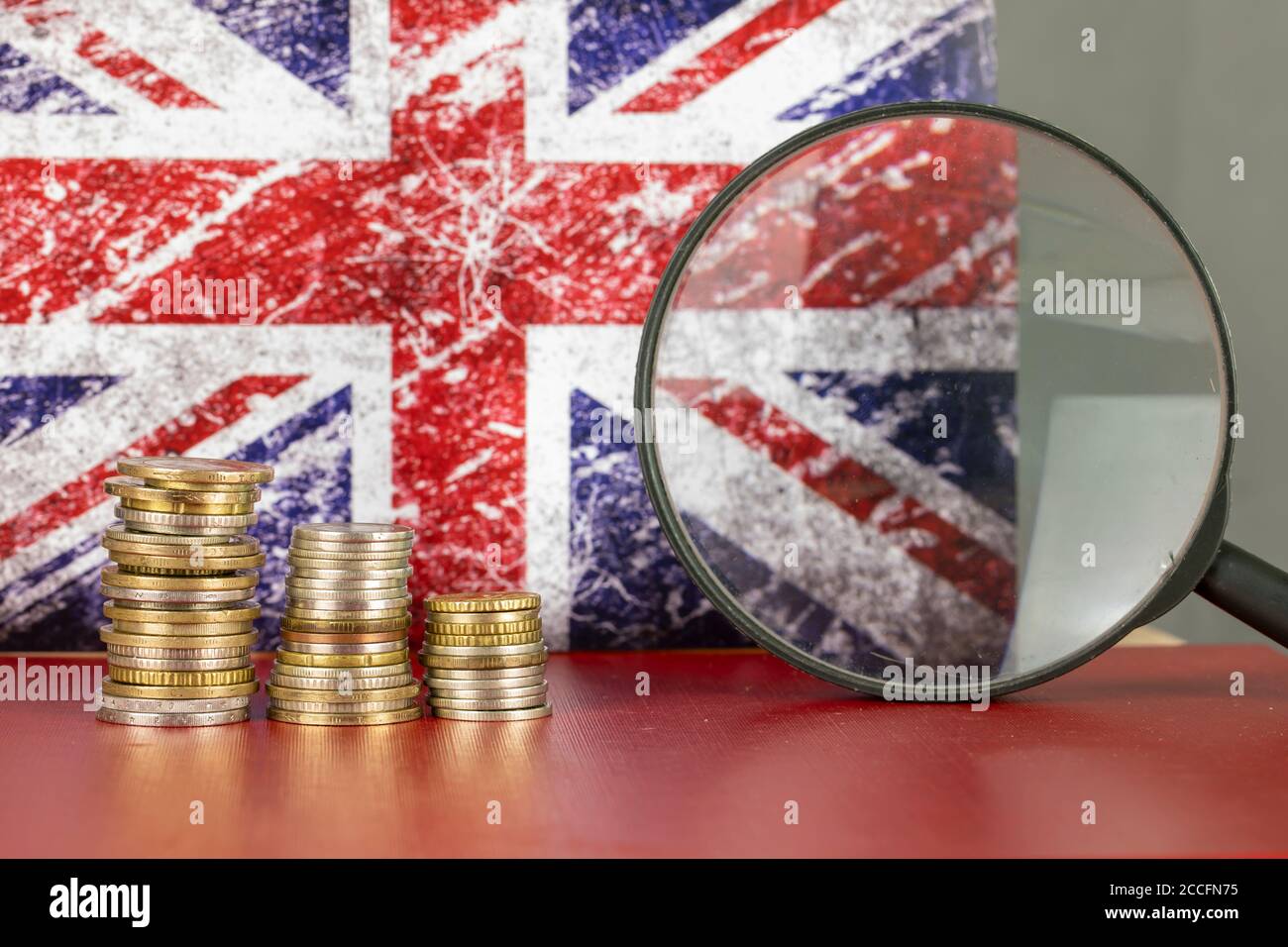 Loupe et pièces en face du drapeau du Royaume-Uni, concept d'économie de pays Banque D'Images