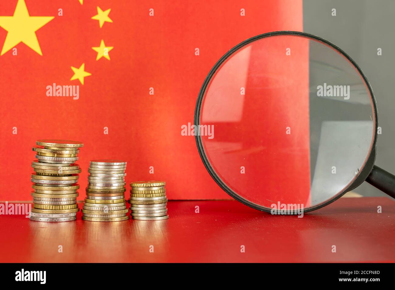 Loupe et pièces de monnaie devant le drapeau de la Chine, concept d'économie de pays Banque D'Images