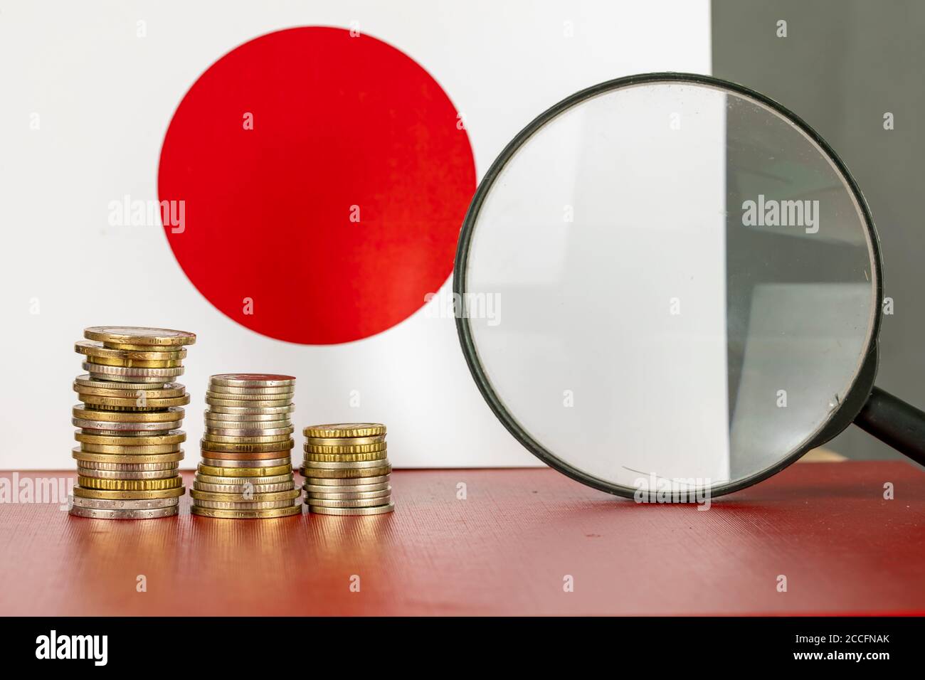 Loupe et pièces en face du drapeau japonais, concept d'économie de pays Banque D'Images