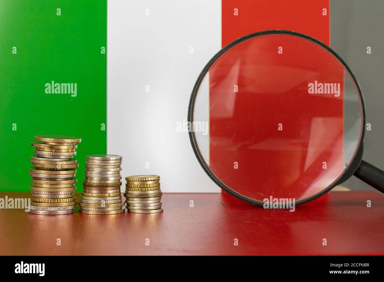 Loupe et pièces de monnaie devant le drapeau de l'Italie, concept d'économie de pays Banque D'Images