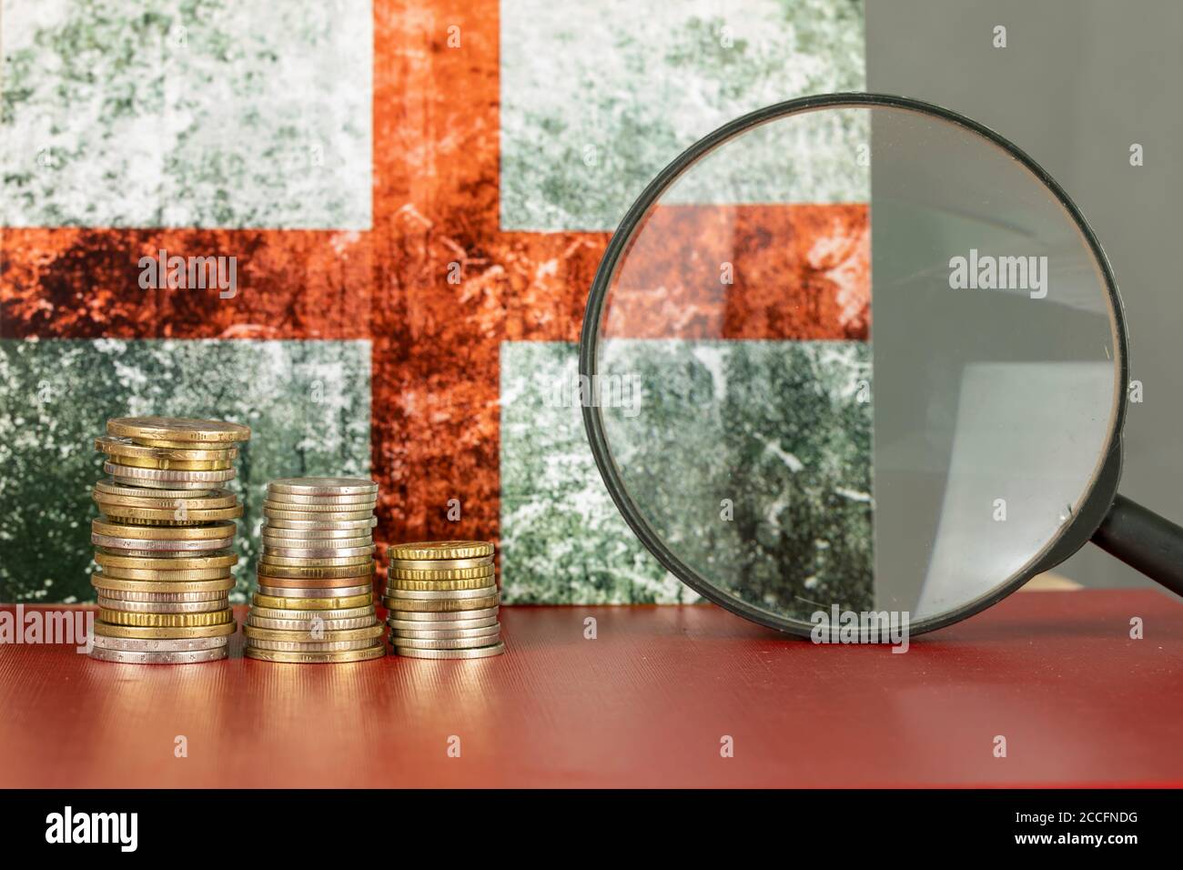 Loupe et pièces de monnaie devant le drapeau de l'Angleterre, concept de l'économie de pays Banque D'Images