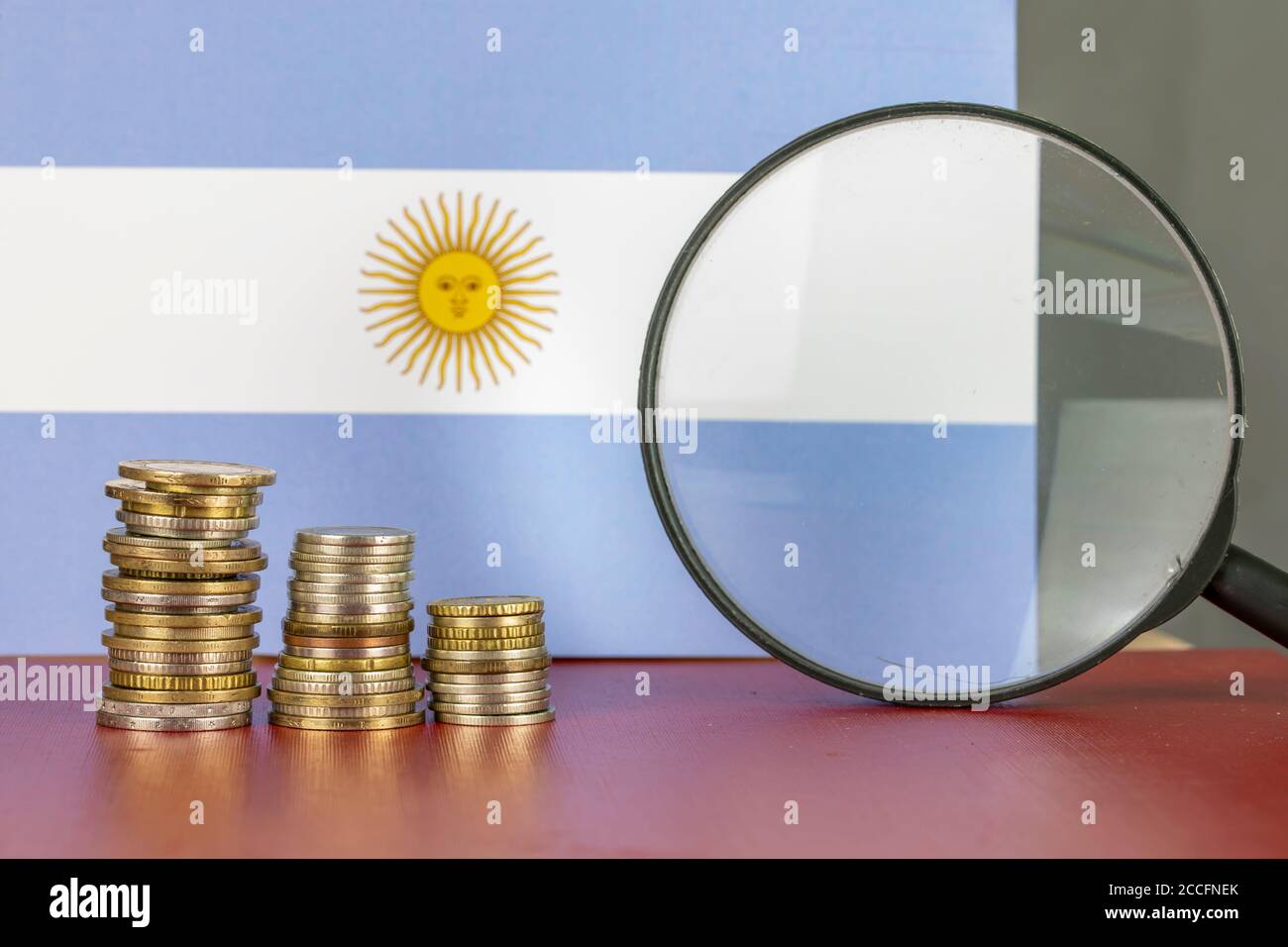 Loupe et pièces de monnaie devant le drapeau argentin, concept d'économie de pays Banque D'Images
