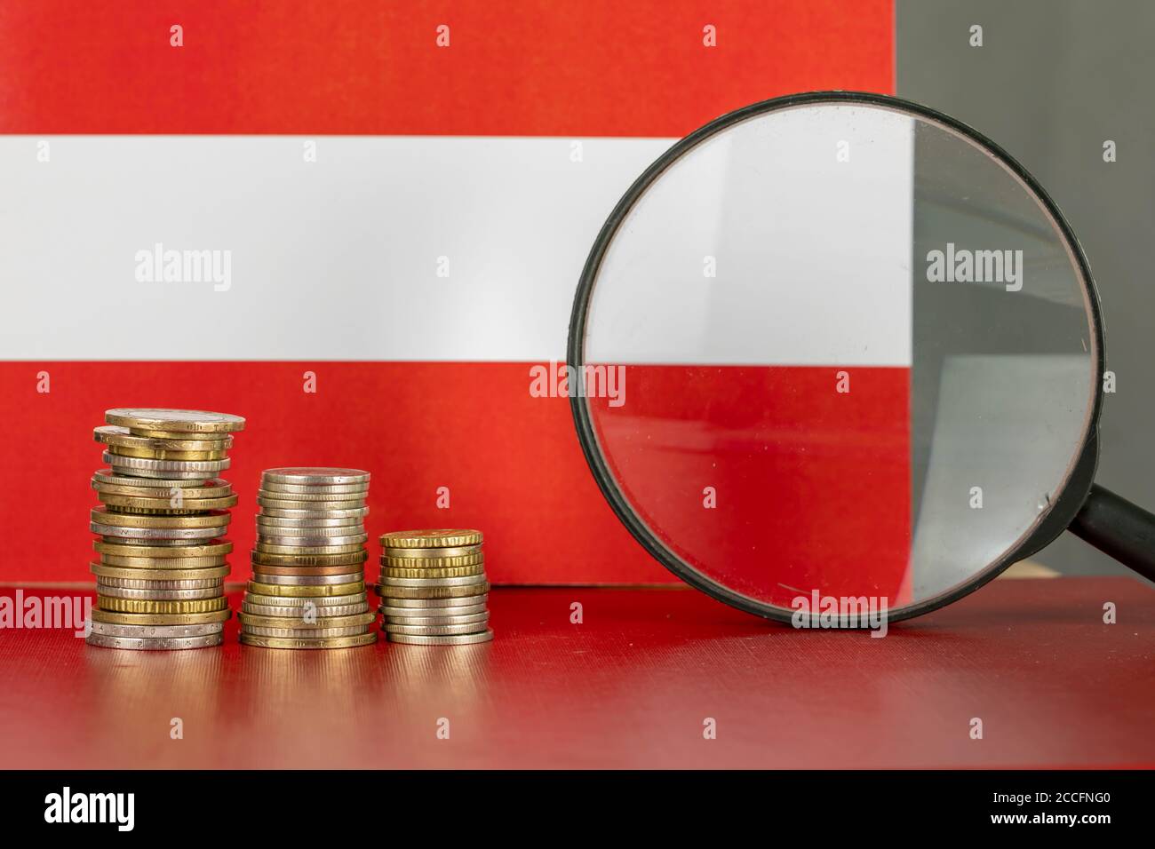 Loupe et pièces en face du drapeau autrichien, concept d'économie de pays Banque D'Images