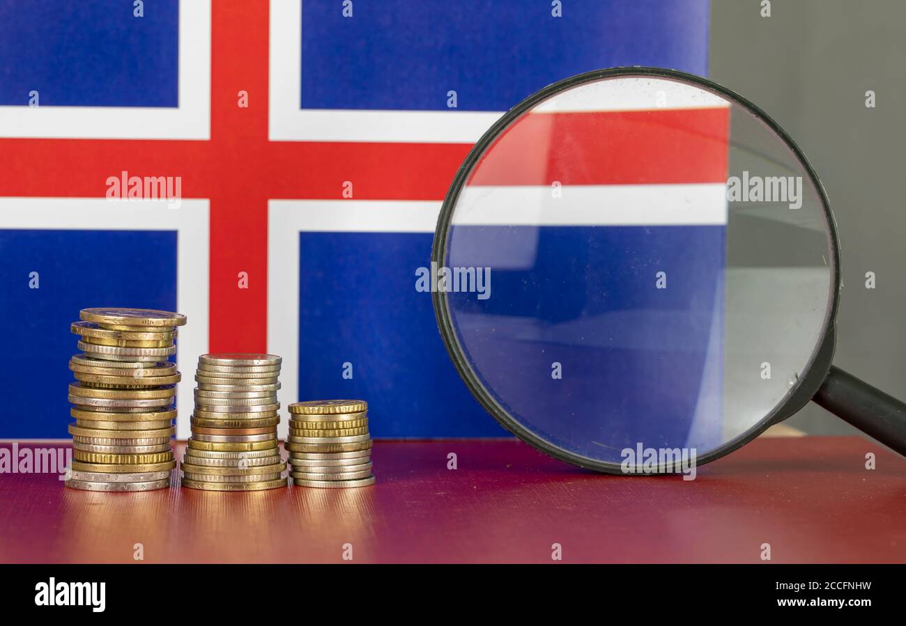 Loupe et pièces en face du drapeau islandais, concept d'économie de pays Banque D'Images