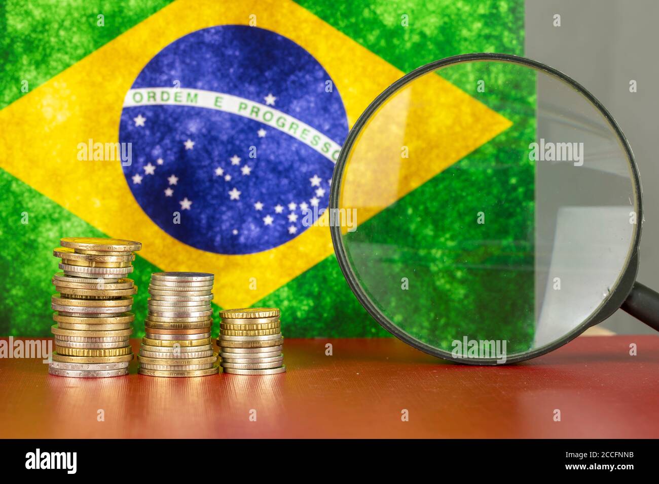 Loupe et pièces en face du drapeau du Brésil, concept d'économie de pays Banque D'Images