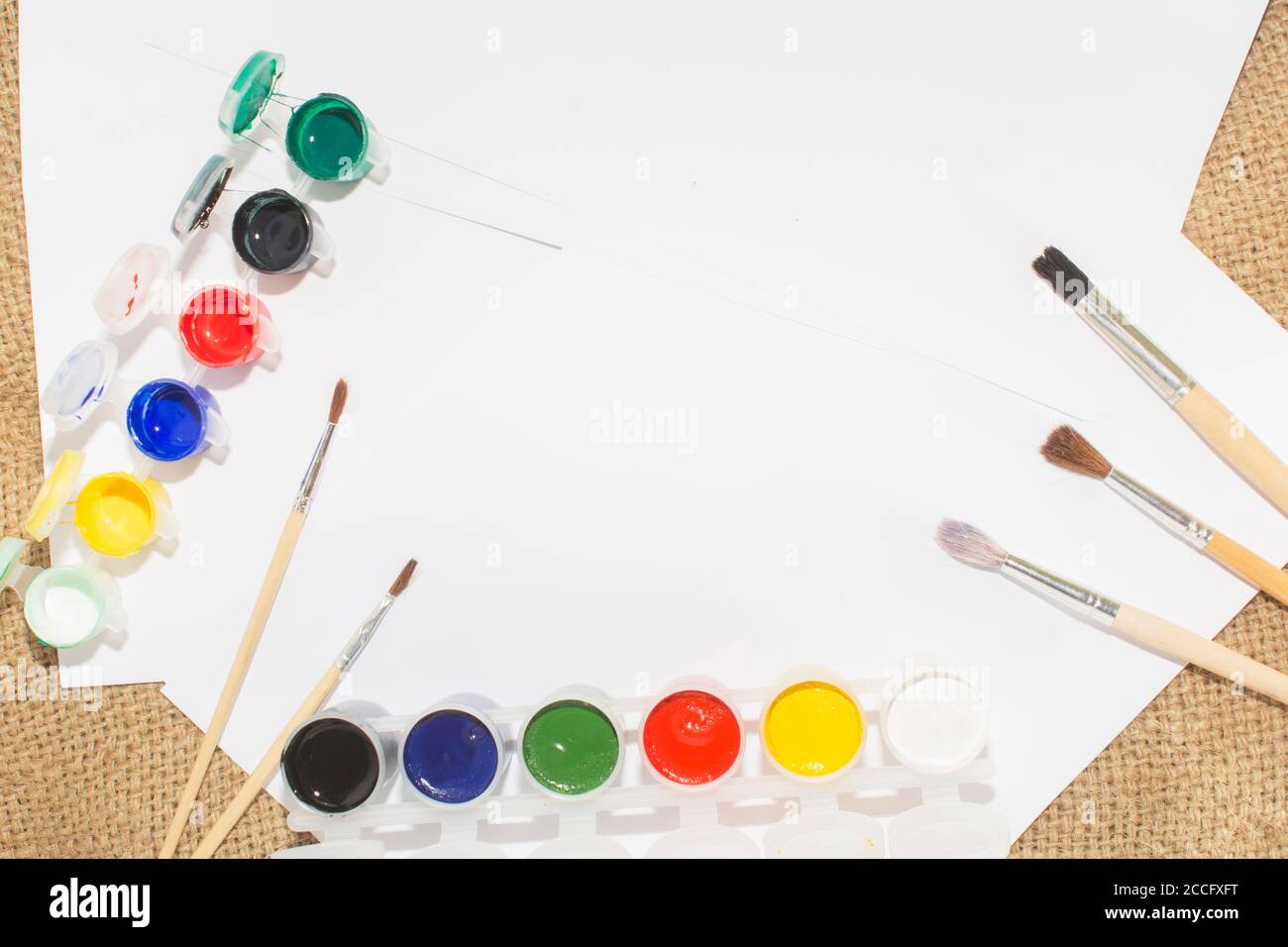 Ensemble de peintures aquarelles, pinceaux pour la peinture et feuille de papier blanc vierge de carnet d'esquisses. Banque D'Images