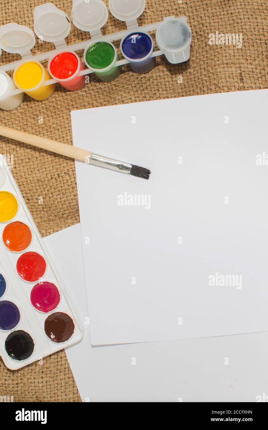 Ensemble de peintures aquarelles, pinceaux pour la peinture et feuille de papier blanc vierge de carnet d'esquisses. Banque D'Images