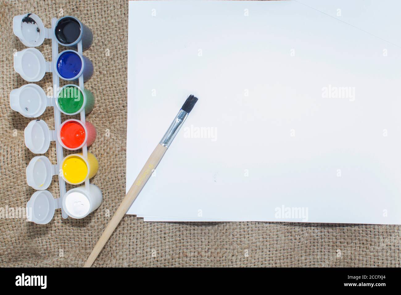 Ensemble de peintures aquarelles, pinceaux pour la peinture et feuille de papier blanc vierge de carnet d'esquisses. Banque D'Images