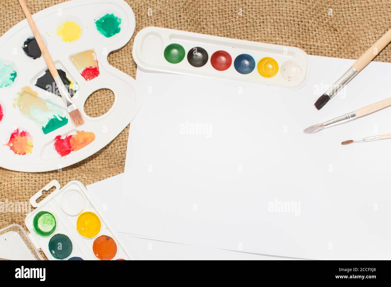 Ensemble de peintures aquarelles, pinceaux pour la peinture et feuille de papier blanc vierge de carnet d'esquisses. Banque D'Images