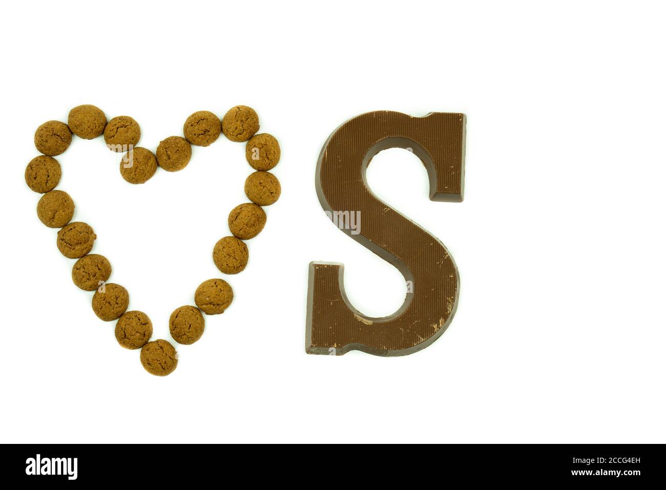Pepernoten traditionnel hollandais en forme de coeur, avec une lettre de chocolat à côté sur un fond blanc. Gâteries qui sont données Banque D'Images