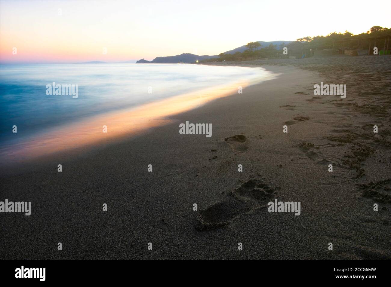 Belle côte méditerranéenne au coucher du soleil avec empreintes digitales dans le sable. Banque D'Images