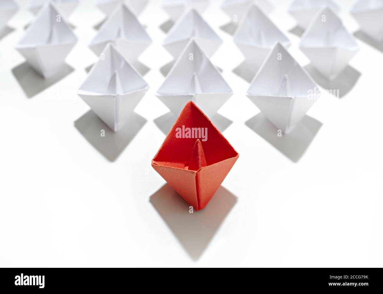 Métaphore du leader. Navire origami rouge avec flotte blanche, isolé sur fond blanc. Banque D'Images