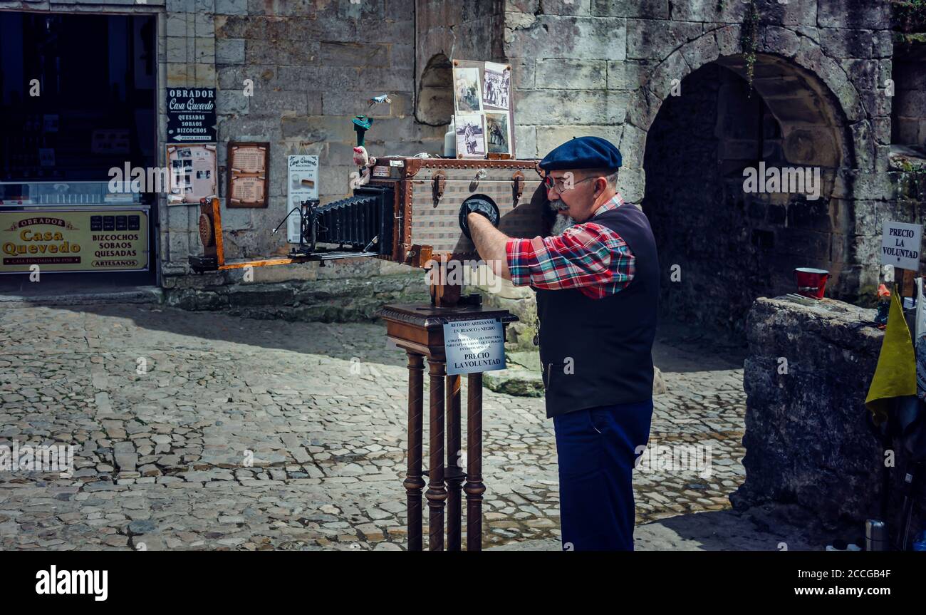 Photographe de rue réglant son appareil photo avant de prendre une photo de touristes Banque D'Images