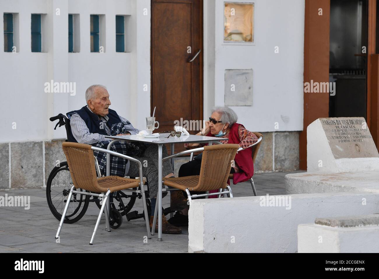 Peu de choses sur la plage de Tamariz à Estoril le 08/21/2020. Deux personnes très âgées, un couple, des retraités, des personnes âgées s'assoient à une table et boivent de l'espresseo et du café glacé, vieux, en fauteuil roulant, fragile, vieux, senior. | utilisation dans le monde entier Banque D'Images