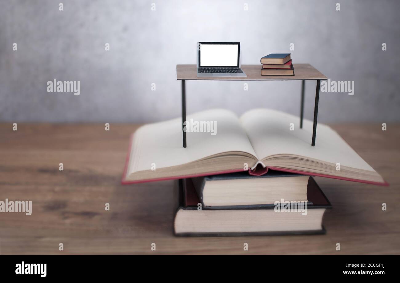 Bureau miniature avec ordinateur portable et livres sur une pile ouverte de livres Banque D'Images