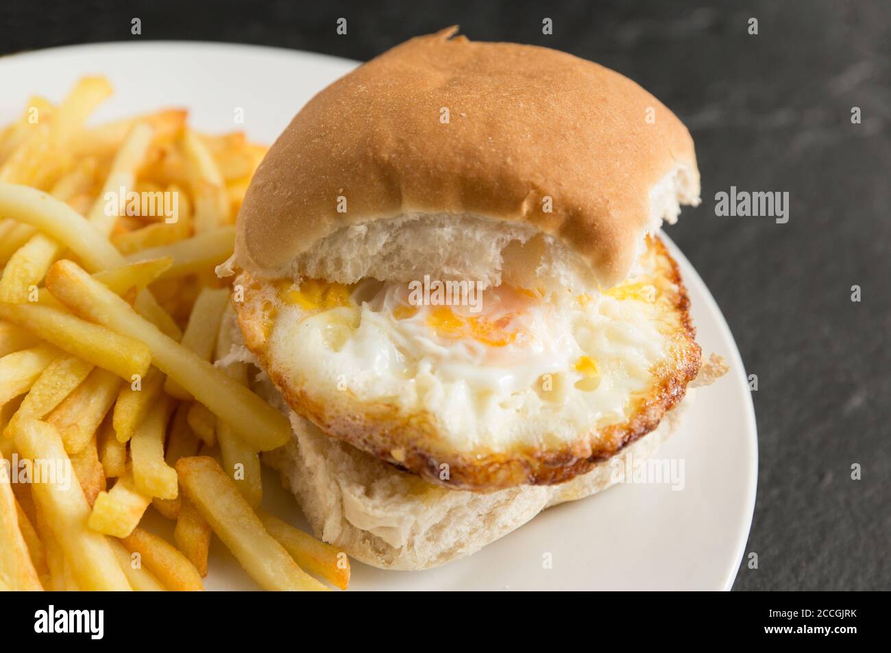Deux œufs frits dans un petit pain avec des frites au four. Angleterre GB Banque D'Images
